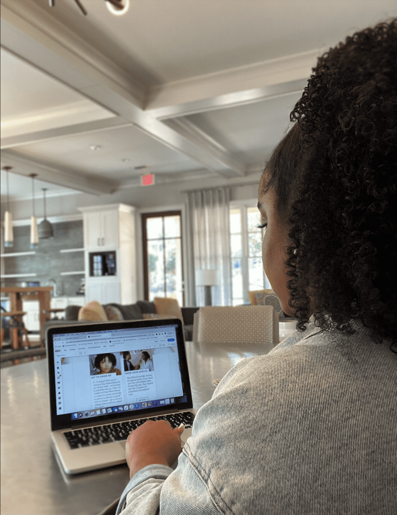 woman working on computer and pictured from behind. A multi-hyphenate working on her craft